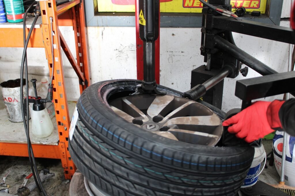 Manos de trabajador Bugauto con material especializado arreglando rueda de vehículo.